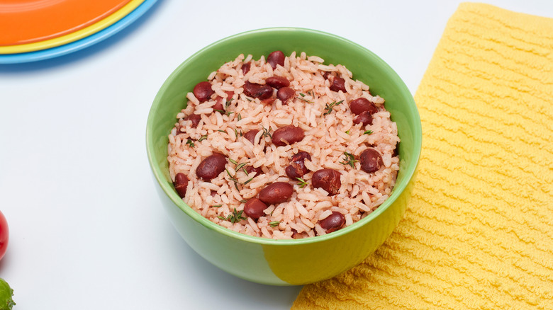 A green bowl of rice and peas with rosemary garnishes