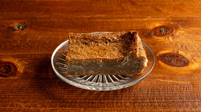A plate with a slice of sweet potato pudding on a wooden countertop