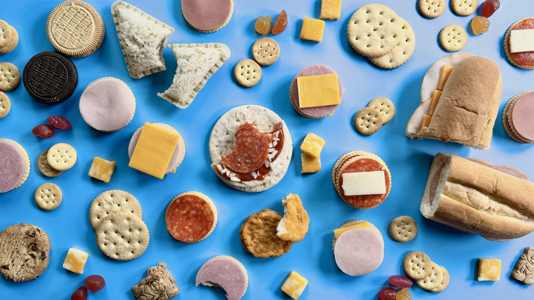 Assorted and scattered Lunchables food items on a blue surface