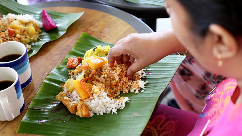 A person eating banana leaf rice at a restaurant.