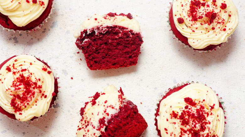 Several red velvet cupcakes and one is cut in half