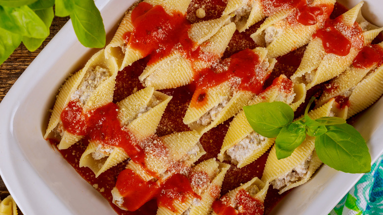 A white tray of stuffed shells with tomato sauce