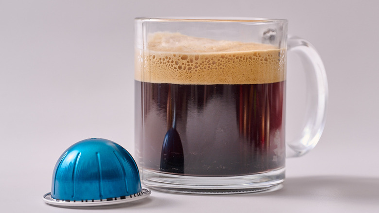 Odacio Nespresso pod and glass of coffee on white table