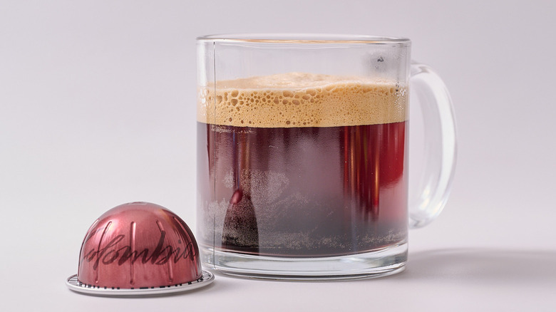 Colombia Nespresso pod and glass of coffee on white table