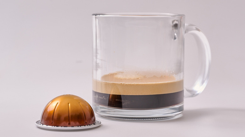 Double Espresso Dolce Nespresso pod and glass of coffee on white table