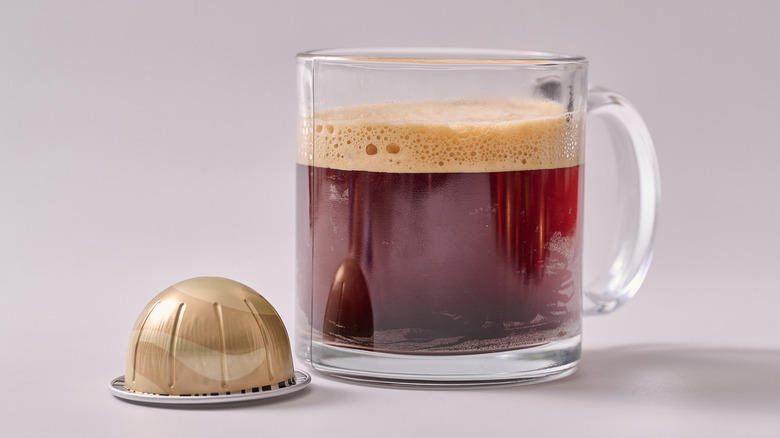 Sweet Vanilla Nespresso pod and glass of coffee on white table