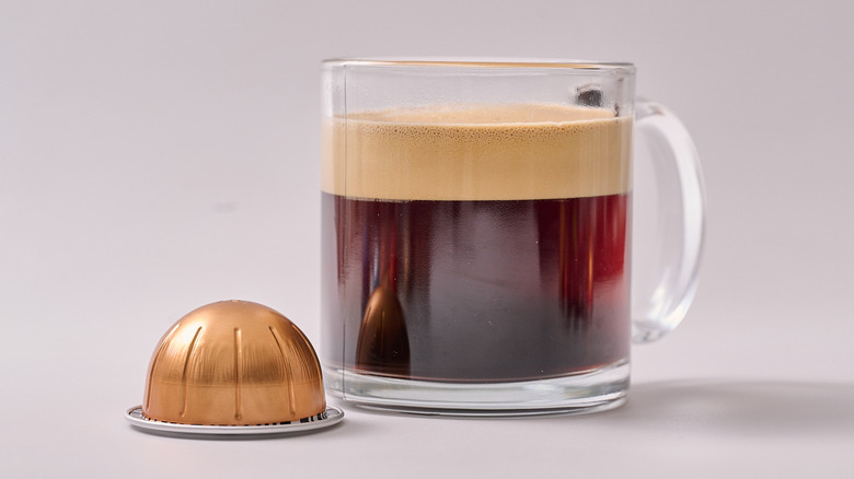 Melozio Nespresso pod and glass of coffee on white table
