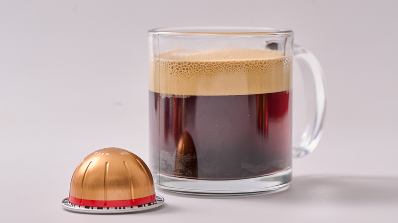 Melozio Decaffeinato Nespresso pod and glass of coffee on white table