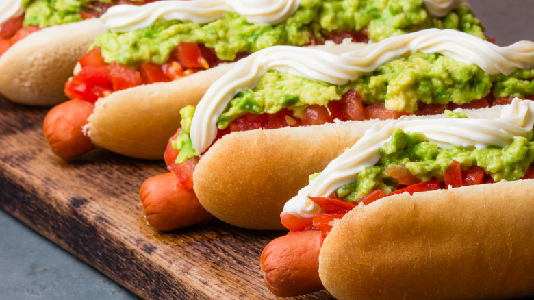 Several completo hot dogs on a wooden cutting board