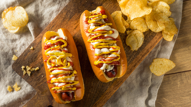 Two Colombian hot dogs on a wooden cutting board