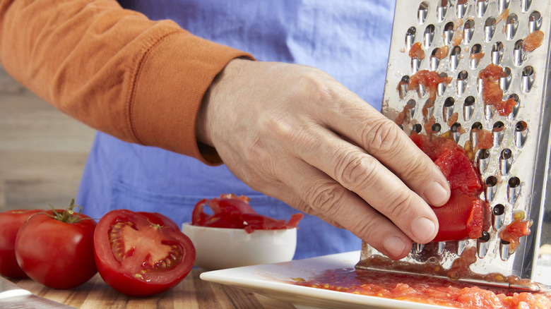 person grating tomatoes