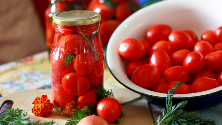 pickled tomatoes in jars with bowl of tomatoes