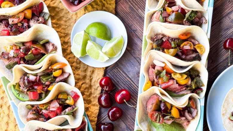 Two platters of grilled flank steak tacos topped with stone fruit salsa