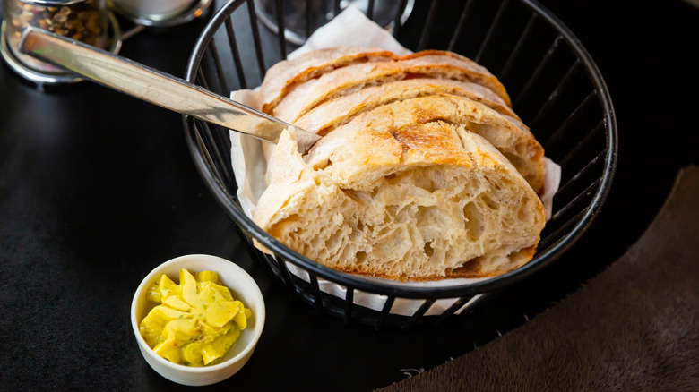 A basket of artisan bread with herb butter at a restaurant