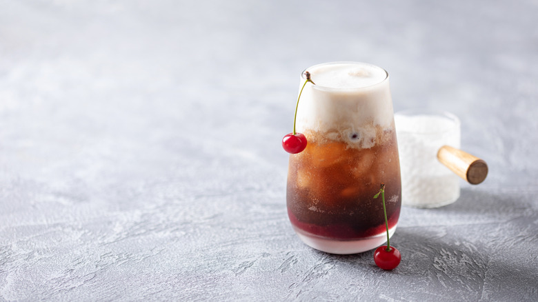 Chocolate-covered cherries dirty soda in a glass garnished with cherries