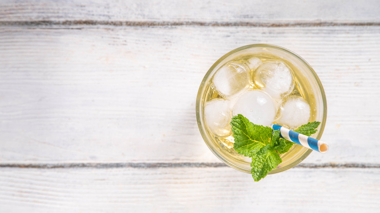 Top view of crème brulée dirty soda drink in glass with straw and garnished with fresh mint