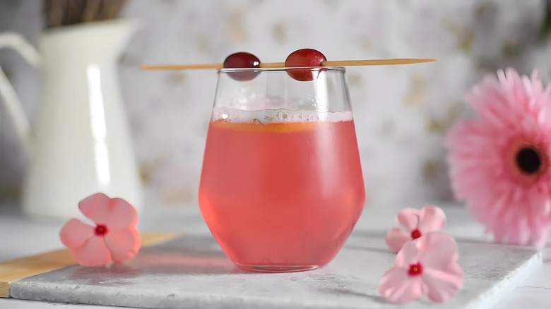 Peanut butter and jelly dirty soda in a wine glass garnished with fresh grapes