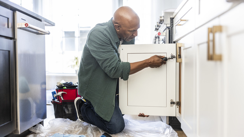 man working on kitchen cabinets at home