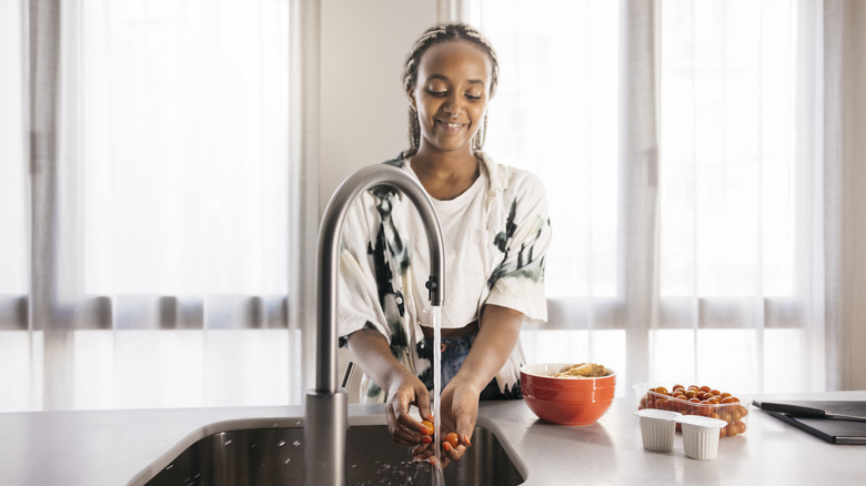 girl washing hands at kitchen sink