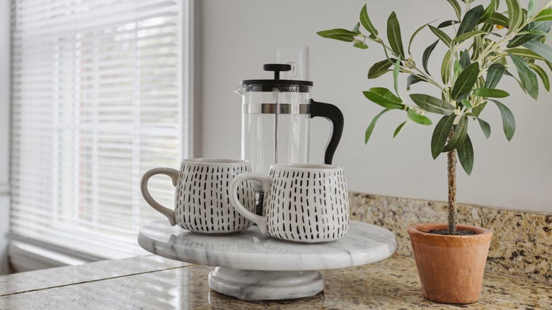 French press and coffee cups on serene counter