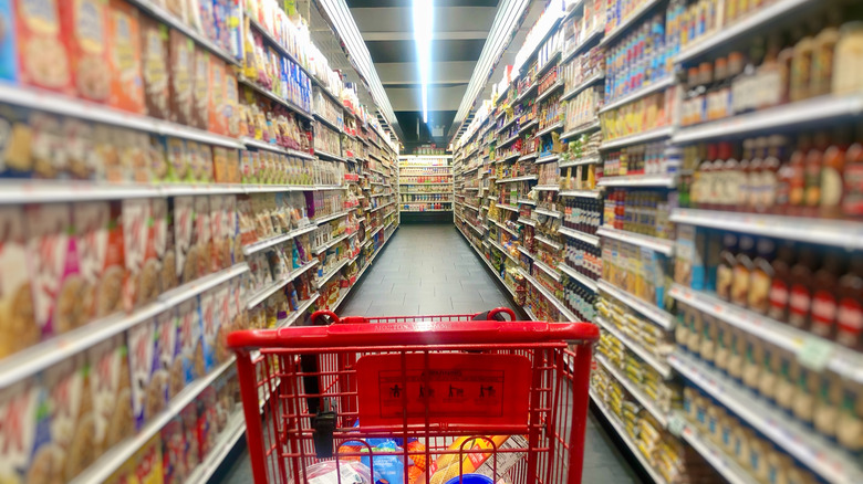 Shopping cart in a long grocery store aisle