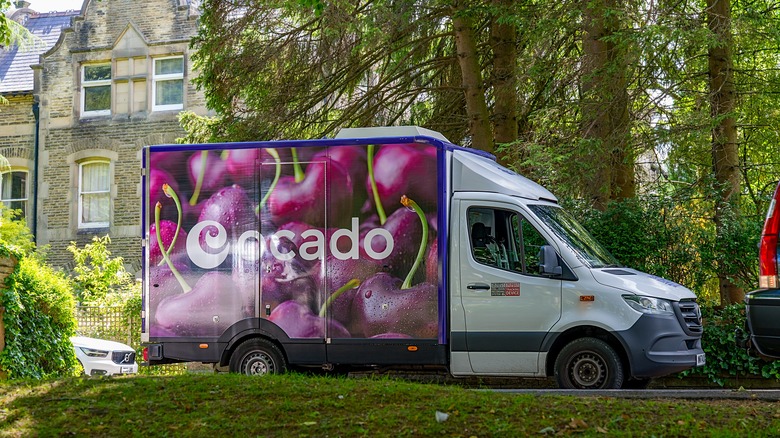 Ocado grocery delivery truck is parked near trees in the UK