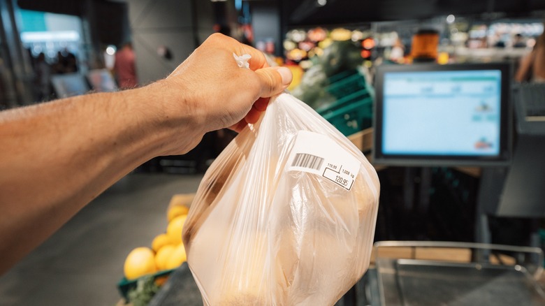 person holding up a plastic grocery bag at a store