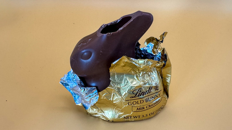 Lindt Milk Chocolate Gold Bunny sitting in partially opened gold foil wrapper on a yellow background