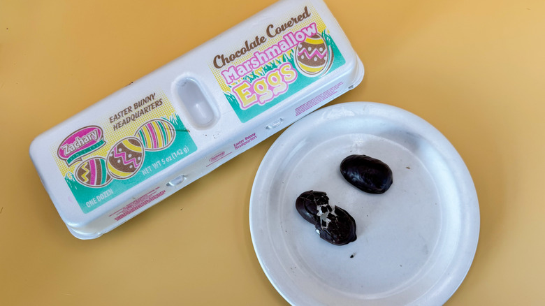 Two Zachary's marshmallow eggs on a white plate next to egg carton packaging on a yellow background