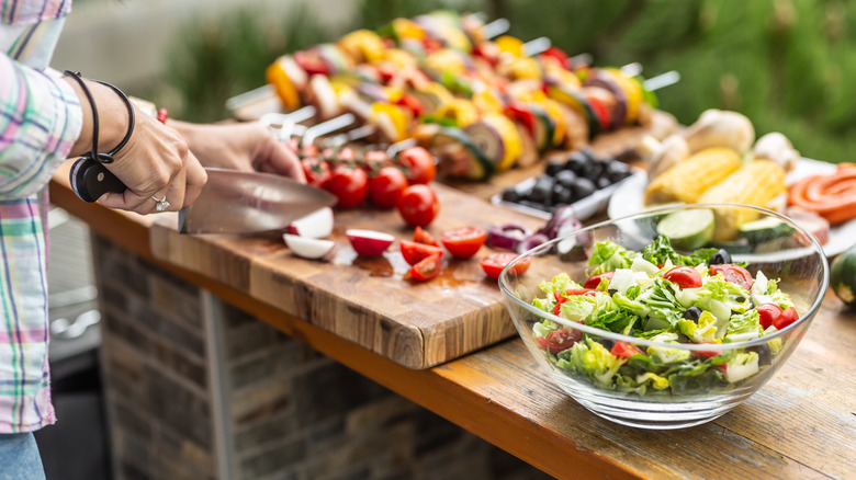 A person chopping salad vegetables at an outdoor station