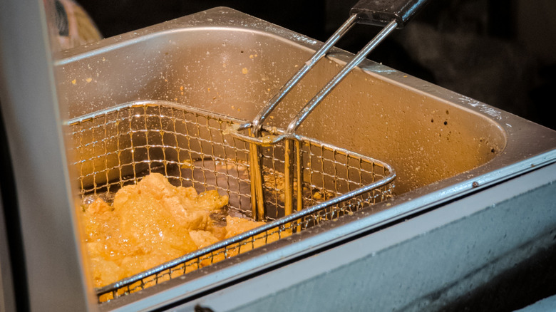 A basket of frying fish in a deep fat fryer