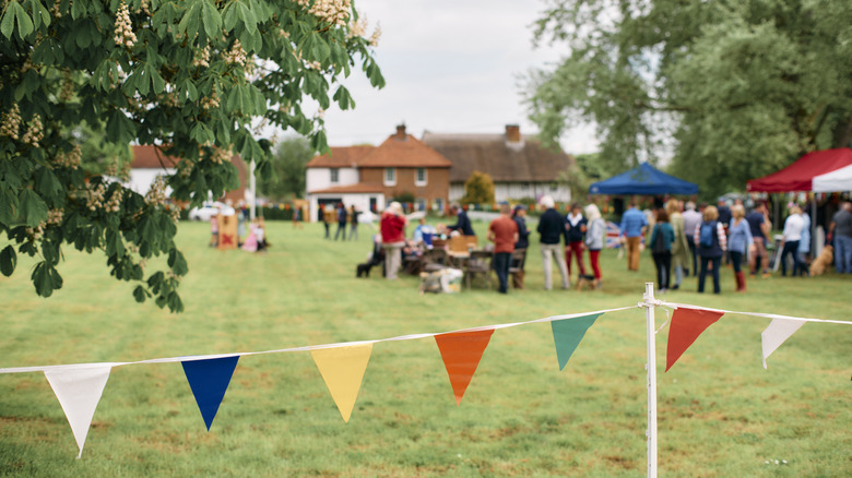 A group of people having a party in a field with flag banners in the foreground
