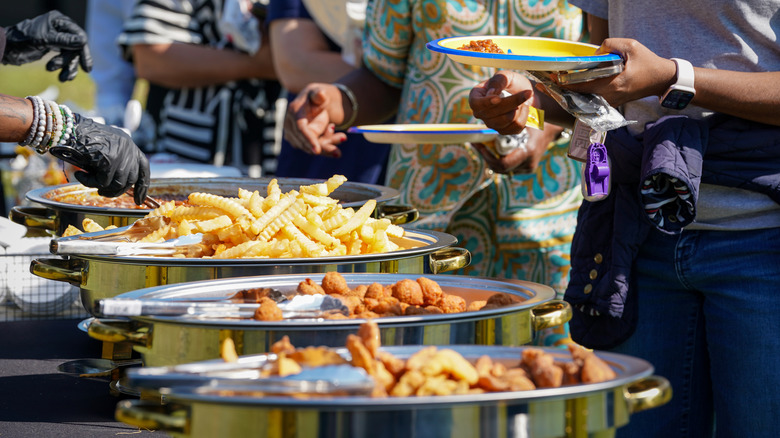 People lining up and being served food at fish fry party