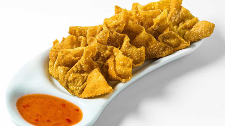 A plate of fried wontons with dipping sauce
