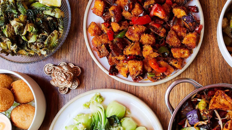 Several vegan Sichuanese dishes from Spicy Moon on a wooden tabletop