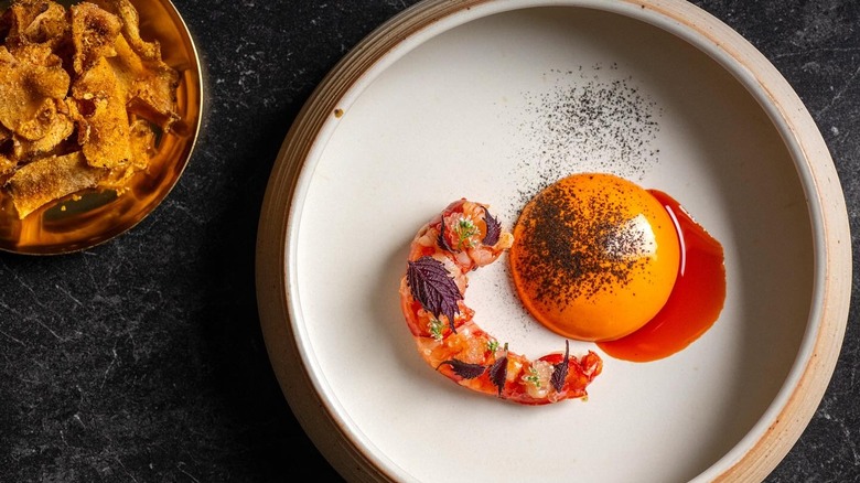 A beautifully plated piece of shrimp with garnishes and sauce from Yingtao