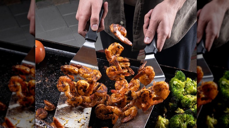Grilling meat on griddle with a pair of tongs
