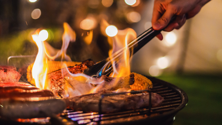 Barbecuing meat in flames at nighttime