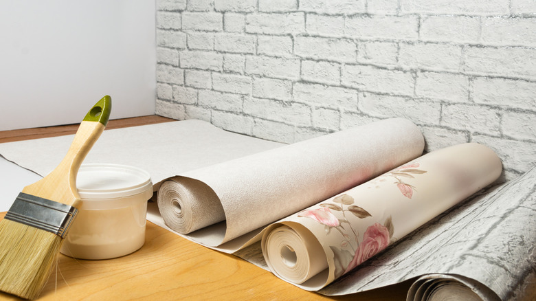 rolls of wallpaper besides brush and glue