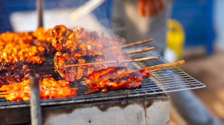 Several sach ko ang (beef skewers) on a grill in Cambodia