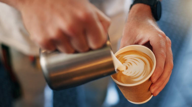 Person pouring latte at a restaurant