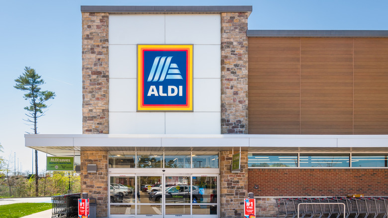 Front of an aldi grocery store with carts lined up on the right of doors.