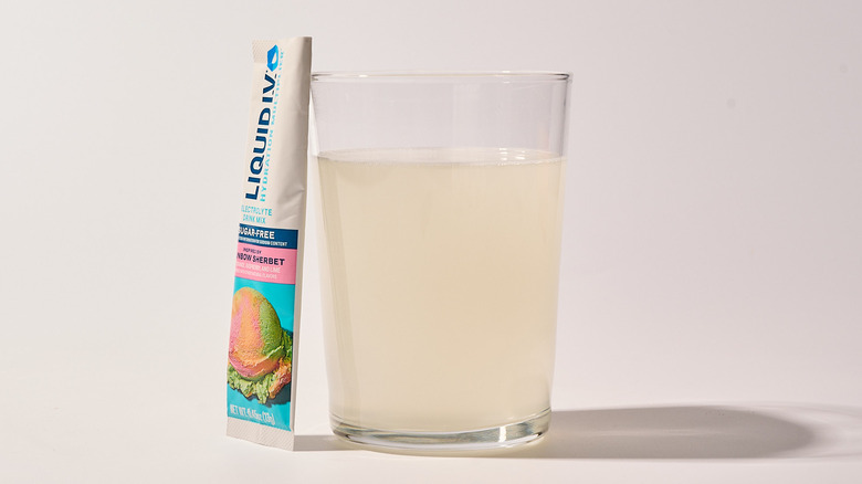 Rainbow Sherbet Liquid I.V. next to a glass of water