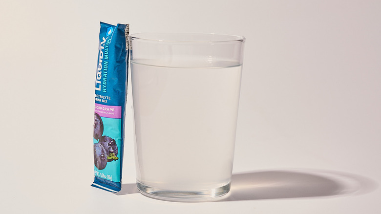 Concord Grape Liquid I.V. next to a glass of water