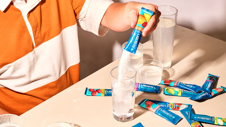 man pouring Liquid I.V. packet into glass of water