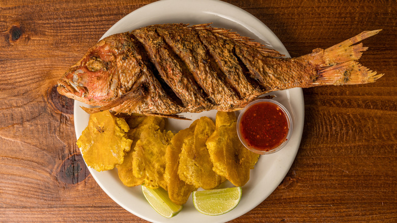 Whole fried red snapper on a plate with fried plantains