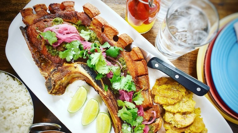 Chuletas kan kan on a platter with fried plantains