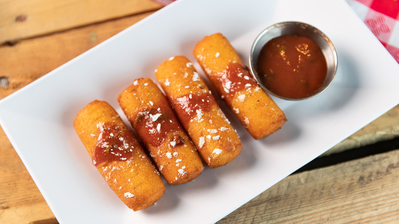 Sorullitos de Maíz on a plate with dipping sauce