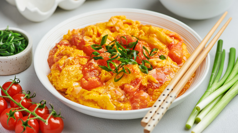 A bowl of Chinese tomato egg with chopsticks