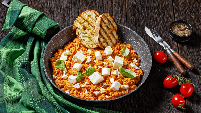 A bowl of Greek strapatsada with bread on a table